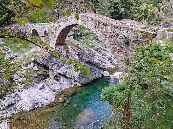 Old Stone Bridge Over Cristal Clear Water In Ticino
