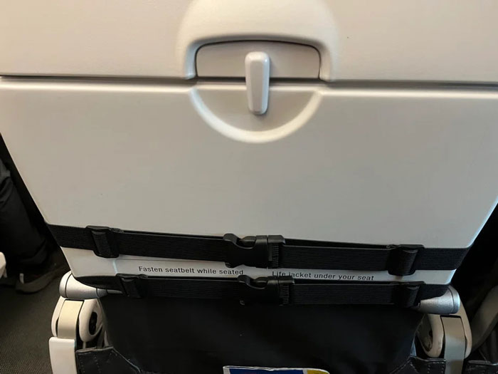 "There is a clip.  Open it": The woman puts an attachment on her seat and this person cannot use her tray table