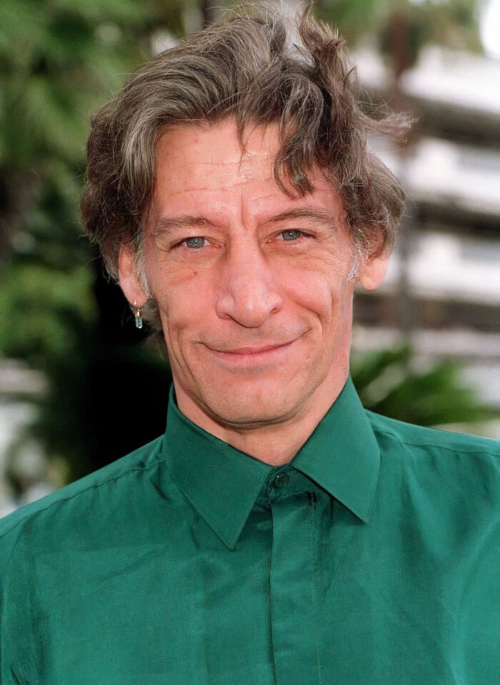 Middle-aged man with tousled hair wearing a green shirt, representing one of the smartest celebrities known for intelligence.