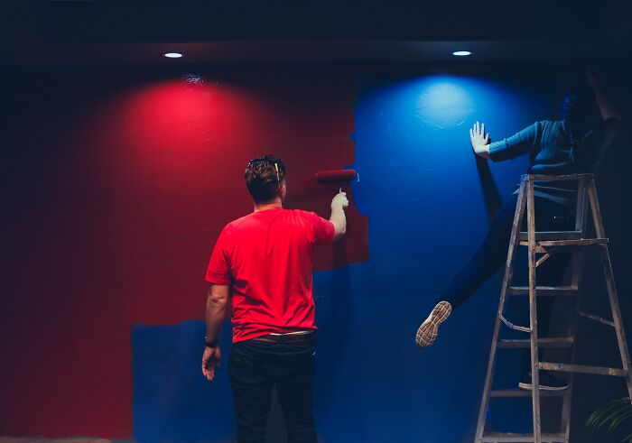 Persons painting walls red and blue