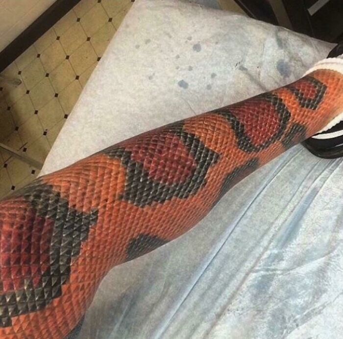 Este tatuaje de piel de serpiente en la pierna de un tipo