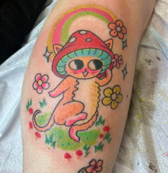 Cat with mushroom hat and flowers arm tattoo