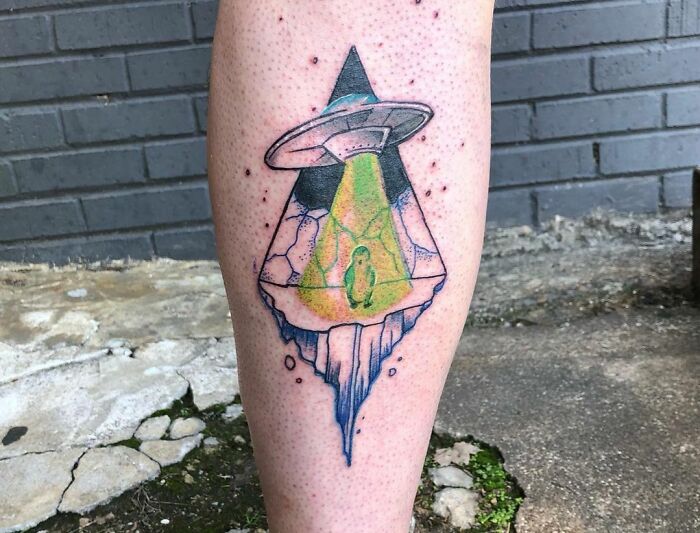 Alien abducting pinguin leg tattoo