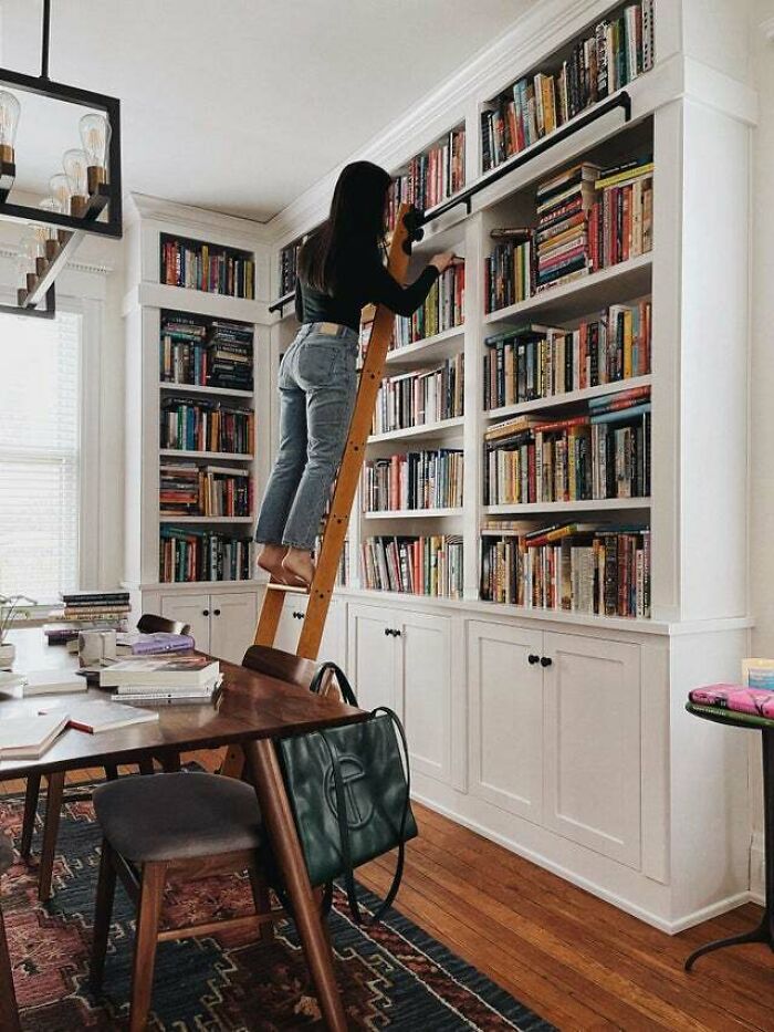 woman on the ladder searching a book 