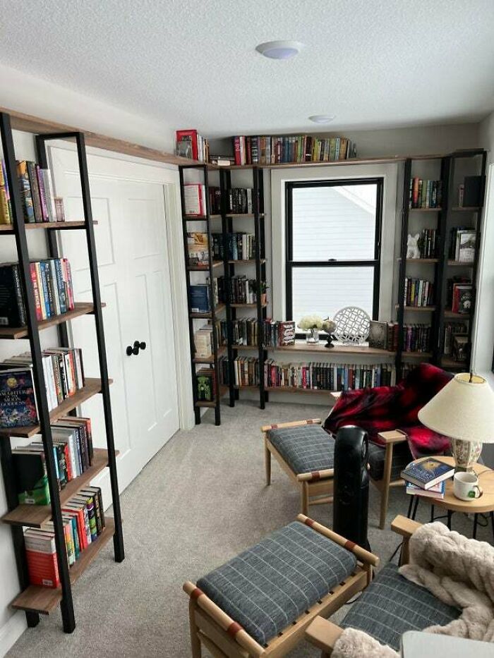 A room with two grey chairs and bookshelves 