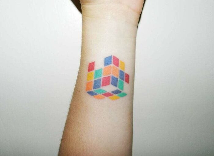 minimalistic tattoo of of a rubik's cube on forearm
