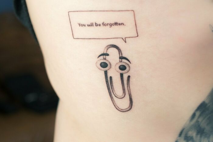 Funny tattoo of a paperclip character with speech bubble saying, "You will be forgotten."