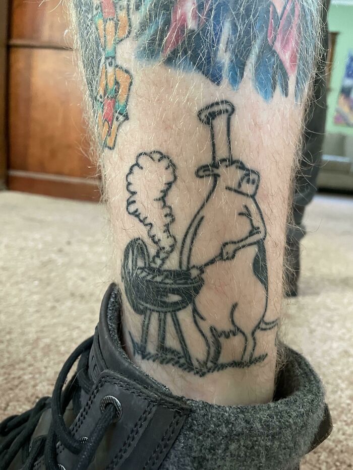 Funny tattoo of a cow barbecuing on a leg, showing creative humor in tattoo art.