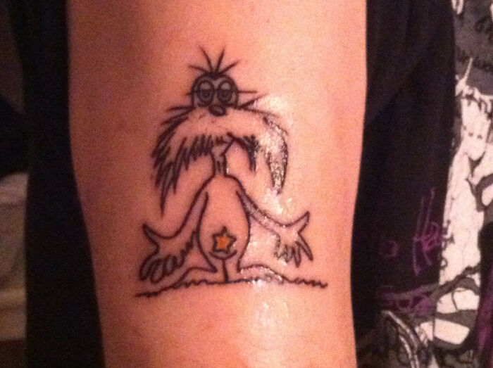 Funny tattoo of a quirky creature with big mustache and glasses on an arm.