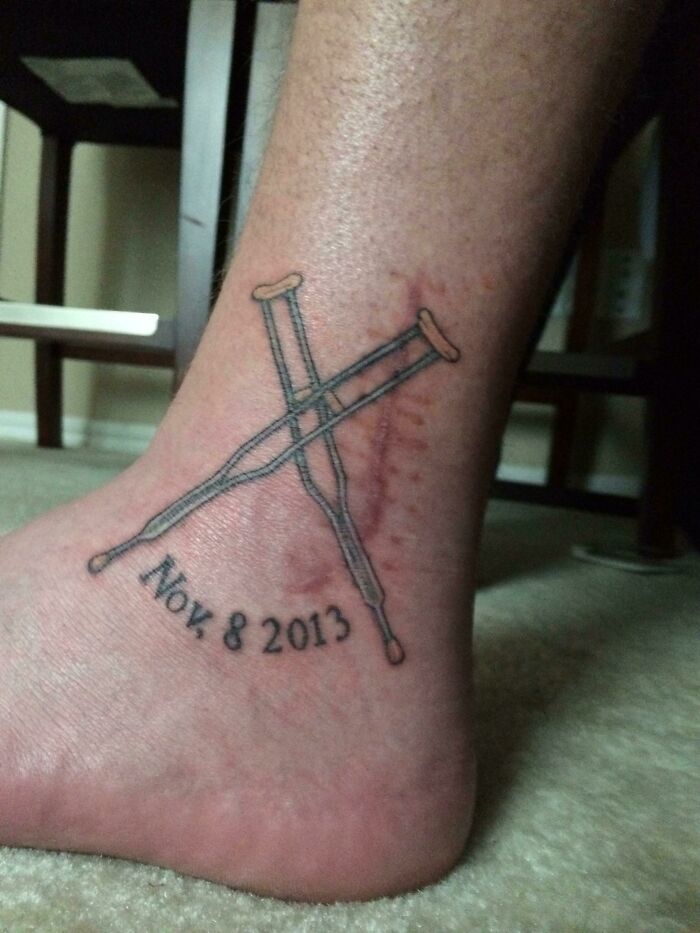 Funny tattoo of crossed crutches with date Nov 8, 2013, on ankle.