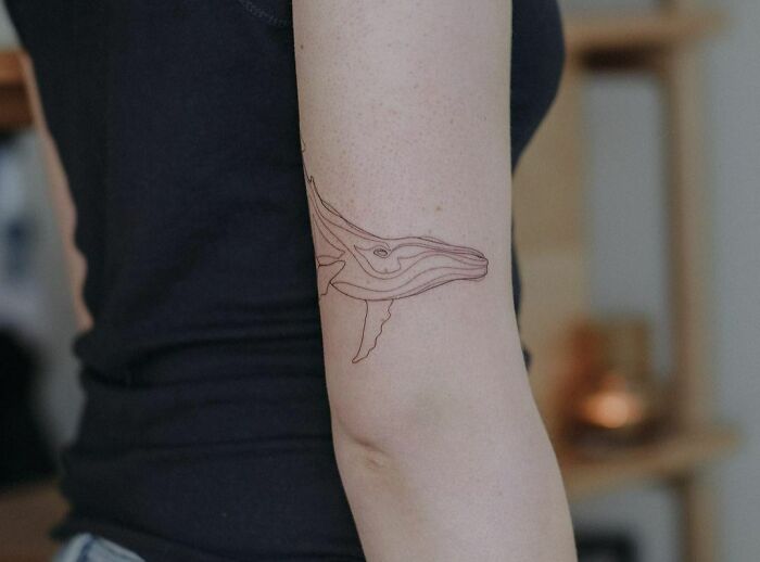 Single line whale tricep tattoo
