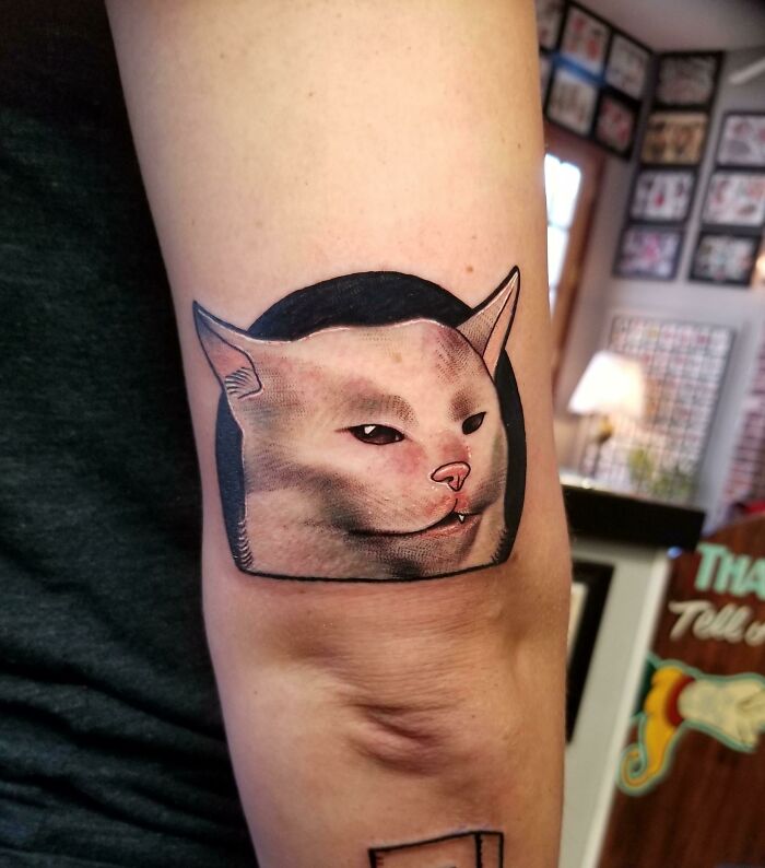 Funny tattoo of a cat's face on a person's arm in a tattoo studio.
