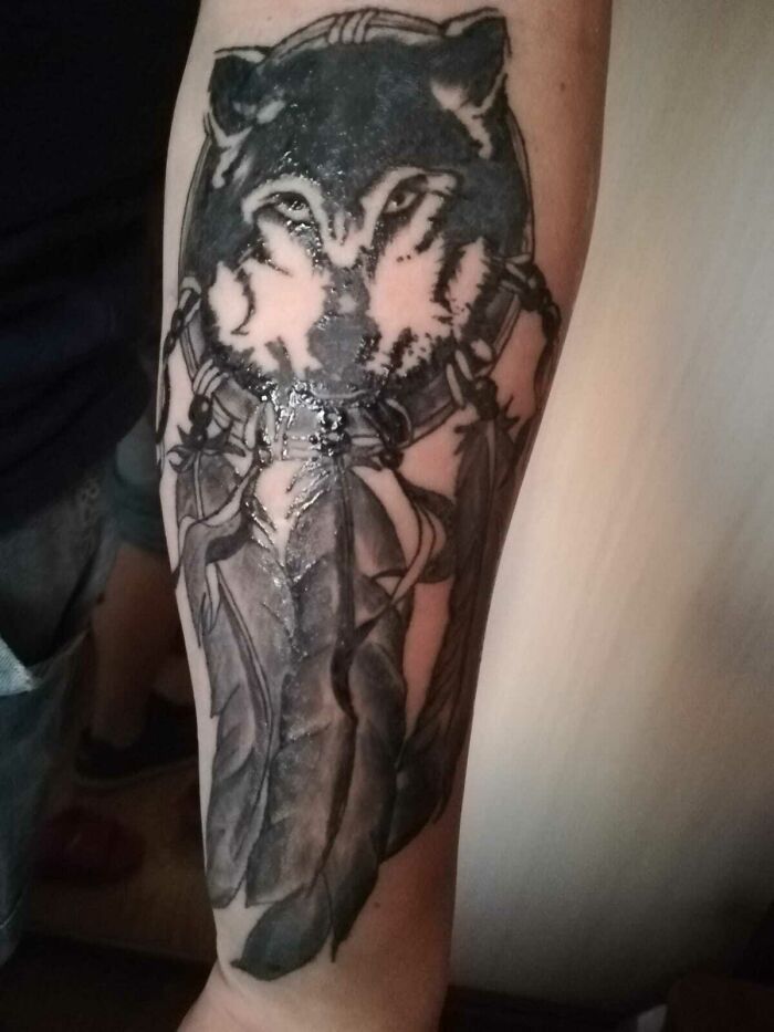 Wolf tattoo with feathers on forearm, blending intricate details that might make you smile.