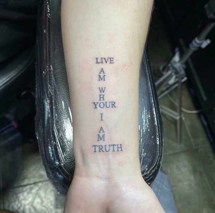 Funny hand tattoo with confusing vertical text design on inner forearm.