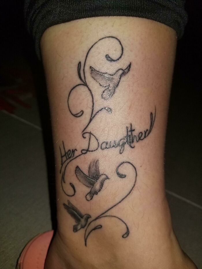 Funny leg tattoo with words, featuring doves and curly lines.