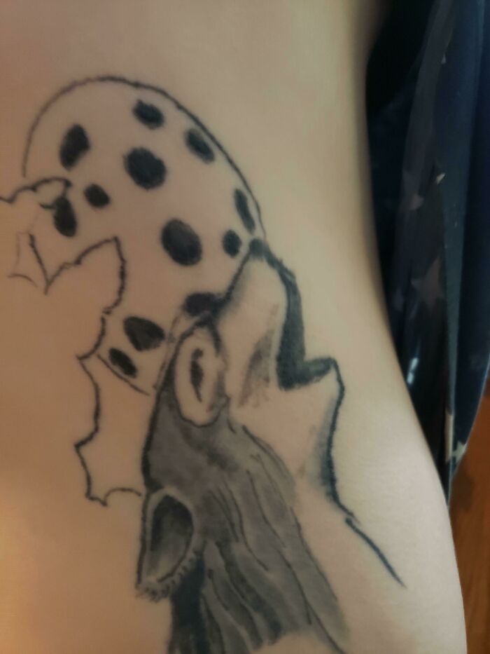 Funny tattoo of a wolf howling at a spotted cookie moon.