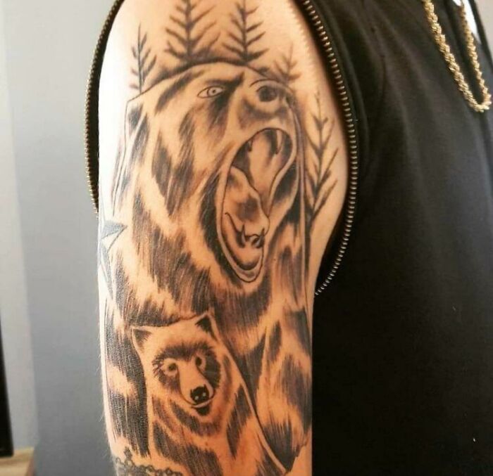 Funny bear tattoo on shoulder with roaring bear and trees, showcasing humorous ink art.