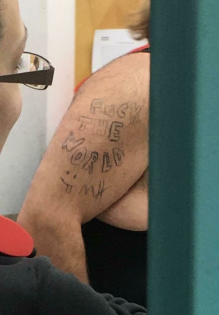 Arm with funny tattoo featuring stylized text and smiley face.