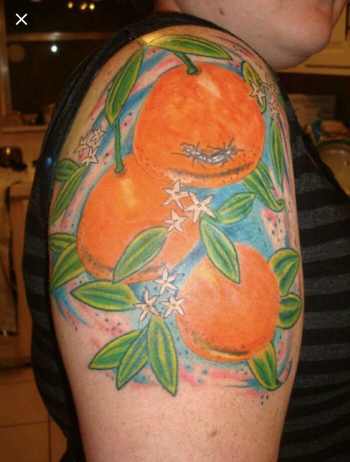 A funny tattoo of vibrant oranges with leaves and flowers on an arm.