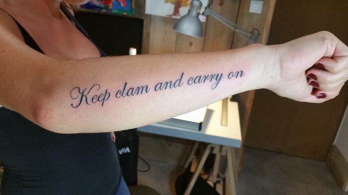 Funny tattoo with misspelled phrase "Keep clam and carry on" on a person's forearm.