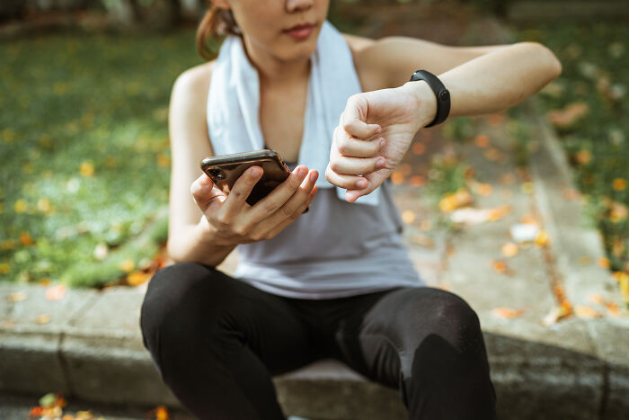 Woman sitting and looking at her watch and phone 