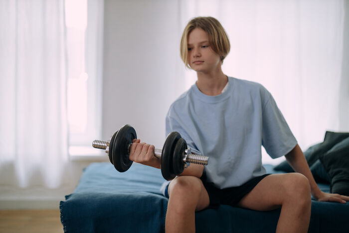 Kid sitting and lifting a dumbbell 