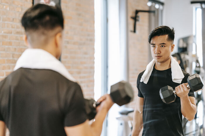 Man standing in front of the mirror and lifting a dumbbell 