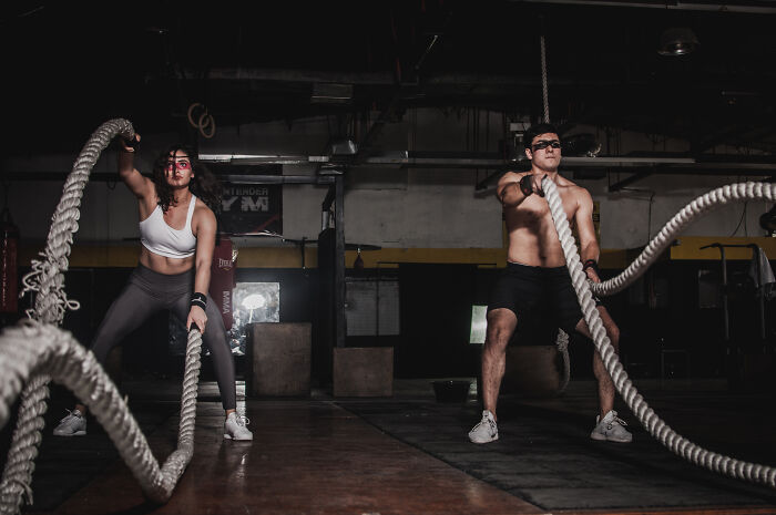 Man and a woman using ropes in the gym 
