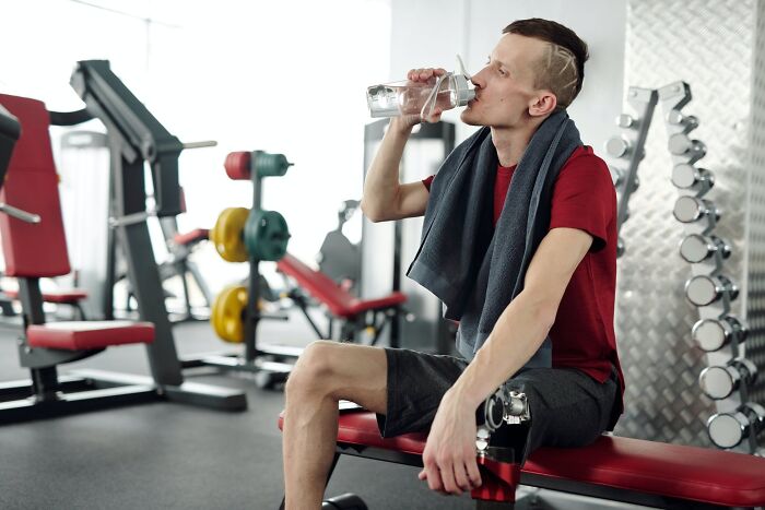 Man sitting at the gym and drinking water 