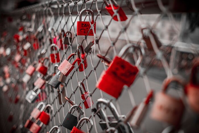 Metal fence filled with red love locks 