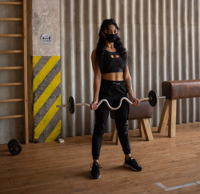 Woman lifting in a gym with a face mask on 