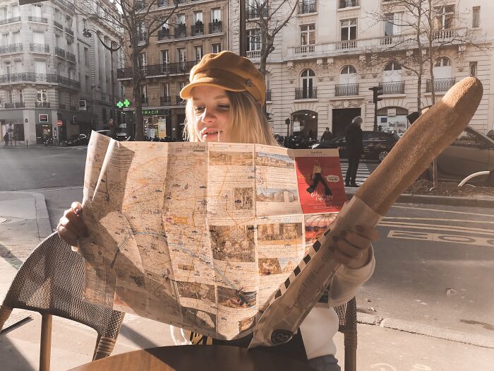 Woman looking at the map and holding a baguette 