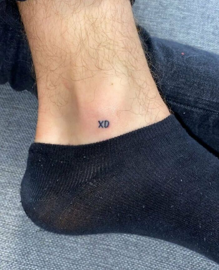 Close-up of a funny tattoo on an ankle with "XD" in bold black letters.