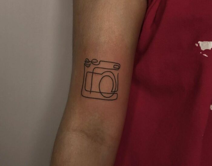 Single line camera arm tattoo