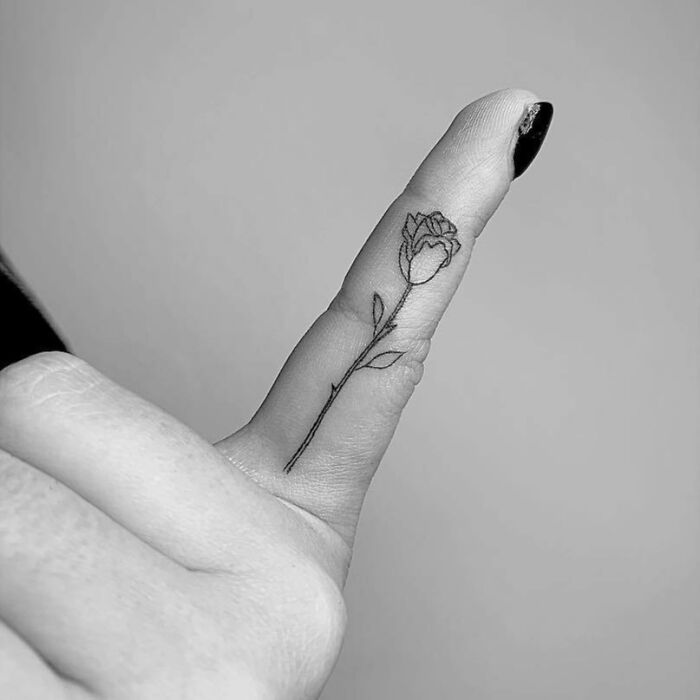 Minimalistic flower tattoo on a finger, representing celebrity tattoos.