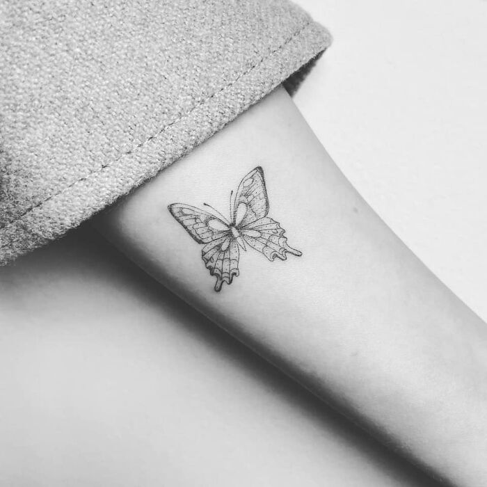 Butterfly tattoo on a person's forearm, showcasing celebrity tattoo art in black and white.