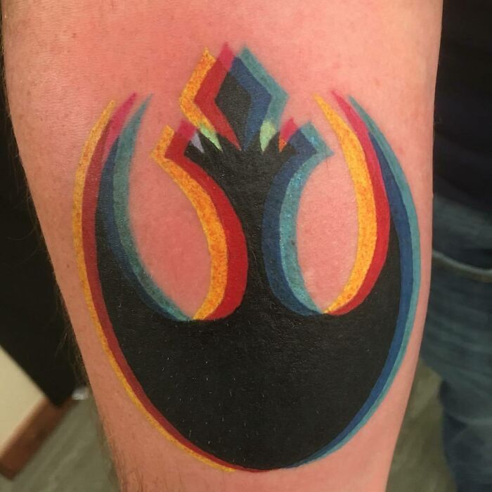 Colorful optical illusion tattoo on arm with layered geometric shapes.