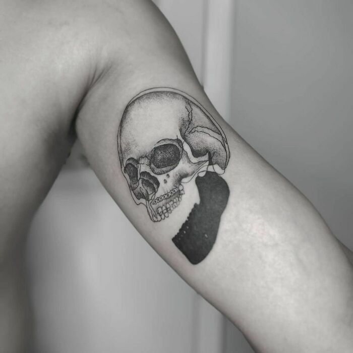 Optical illusion tattoo of a skull on an arm, showcasing detailed shading and depth for visual effect.