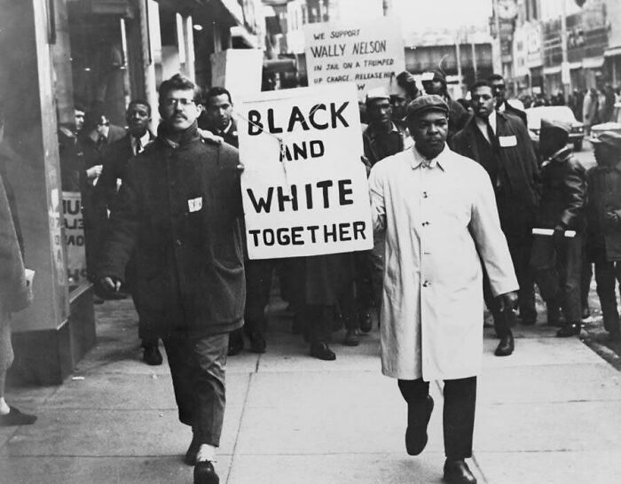 Un hombre blanco y otro negro liderando una marcha por los derechos civiles a finales de la década de los 50