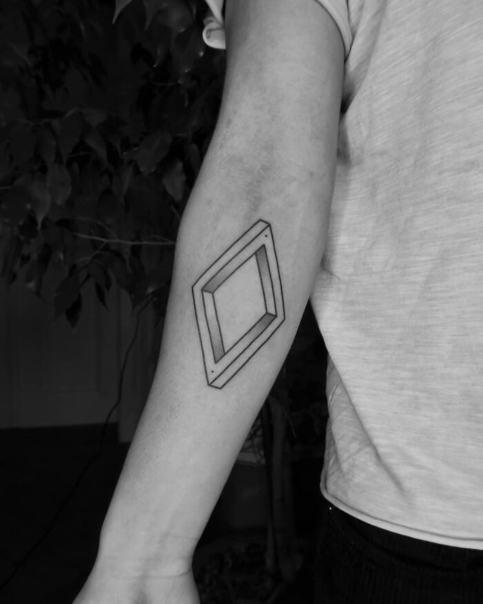 Geometric optical illusion tattoo on a forearm, creating a 3D effect.