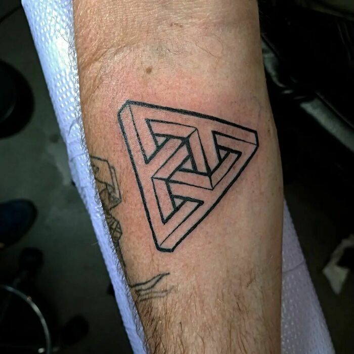 Optical illusion tattoo of a geometric design on a forearm creating a 3D effect.