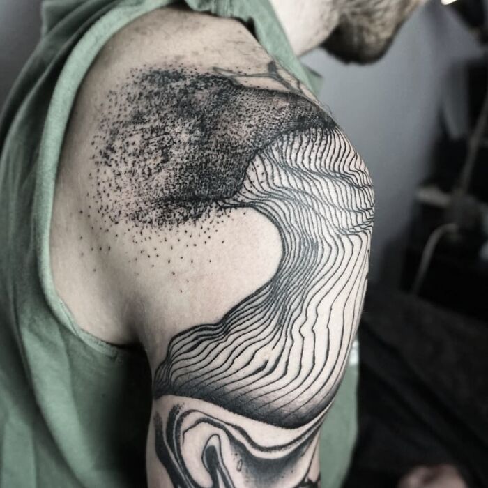 Optical illusion tattoo with swirling lines and patterns on a person's upper arm, creating a dynamic visual effect.