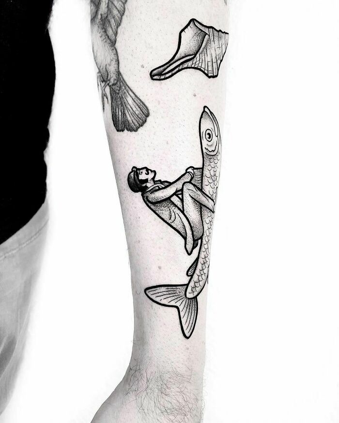 Funny tattoo of a man riding a fish on someone's arm.
