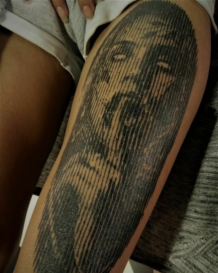Optical illusion tattoo on a leg creating a face using vertical lines.