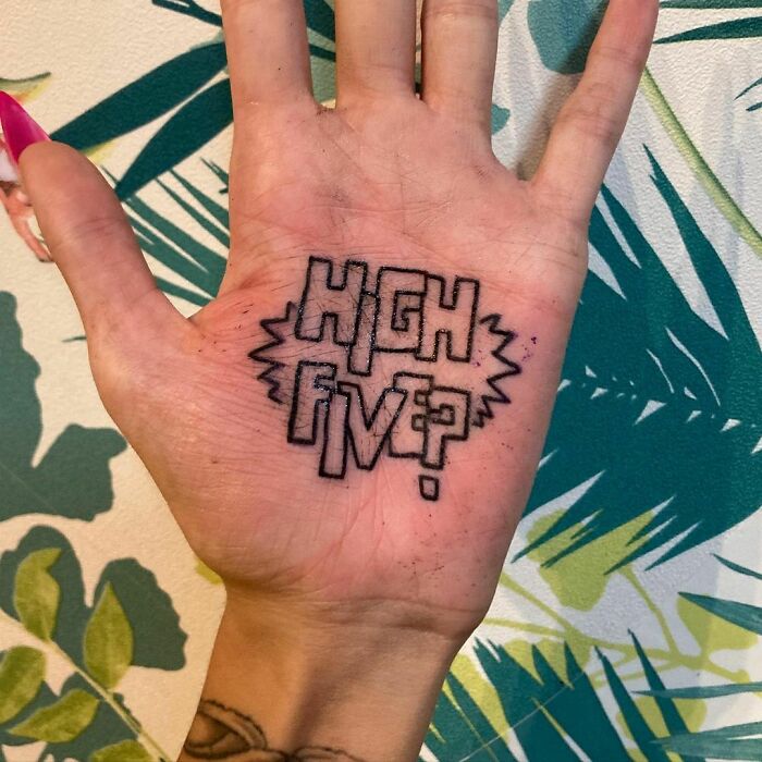 Hand tattoo with the words "High Five?" on the palm, showcasing a funny tattoo design.