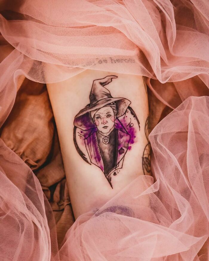 Harry Potter tattoo featuring a wizard in purple tones surrounded by pink fabric.