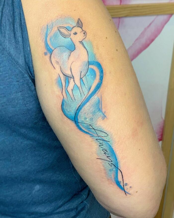 Harry Potter tattoo featuring a doe Patronus with blue watercolor accents and "Always" text on a person's arm.