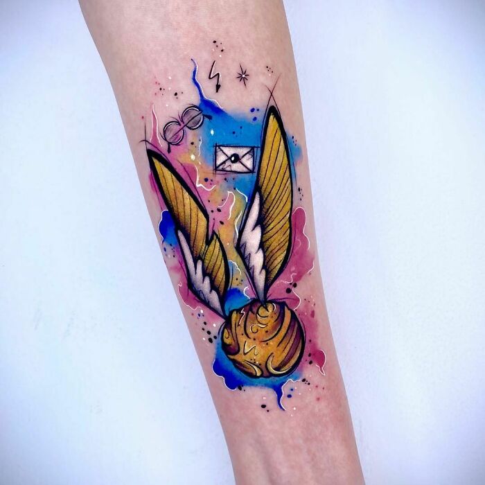 Golden Snitch tattoo with glasses and letter in colorful design, perfect for any Harry Potter fan.
