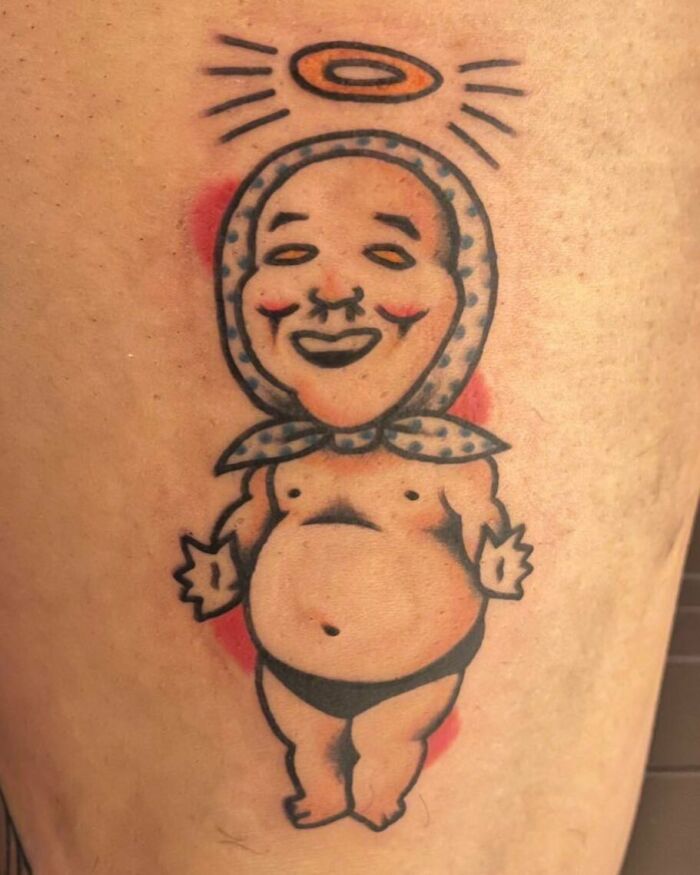 Funny tattoo of a smiling cherub with a bonnet and halo, designed to amuse and entertain.