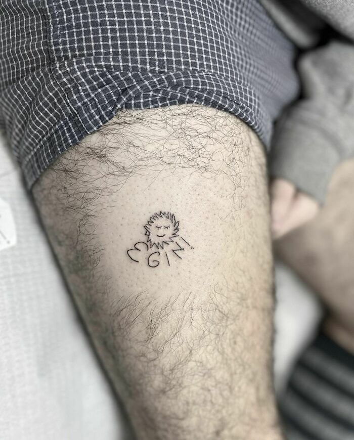 Funny tattoo of a smiling sun with the text "I ❤️ GIN" on a person's leg.